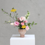 A burst of seasonal charm delicately captured in a sculptured floral arrangement, thoughtfully designed to bring joy to any occasion. Nestled within a charming compot vase, this small yet enchanting creation embodies the essence of the season with its vibrant colors and carefully selected blooms. A perfect gift.